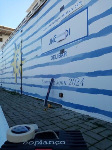 Vinil aplicado em tapumes com design azul e branco na obra Amorim Luxury Comporta.